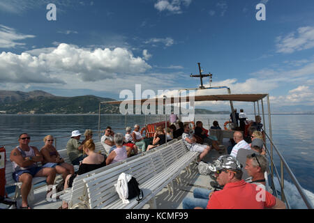 Urlauber oder Touristen auf einer Bootsfahrt in Korfu, Griechenland an einem hellen, sonnigen und leicht bewölkt Tag nahe der Berge. Stockfoto