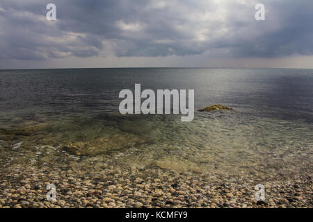 Closeup Kieselsteine am Strand mit Soft Focus vom Meer, Wellen und Skyline Stockfoto