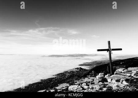 Ein hölzernes Kreuz auf der Spitze des Monte Subasio Berg, mit einem Meer von Nebel unten Stadt Assisi (Umbrien) im Hintergrund und Stockfoto