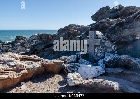 Namenlose Grab und Kreuz in der natürlichen Einstellung zwischen Felsen und Meer im Hintergrund, Lüderitz, Namibia, Afrika Stockfoto