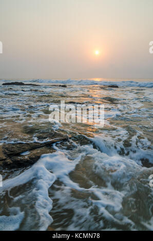 Schönen Sonnenaufgang mit weichem Licht und nassen Felsen am Strand des Atlantischen Ozeans, Ghana, Westafrika Stockfoto