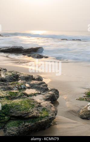 Schönen Sonnenaufgang mit weichem Licht und nassen Felsen am Strand des Atlantischen Ozeans, Ghana, Westafrika Stockfoto