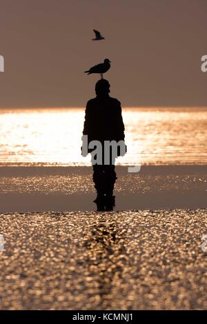 Sir Antony Gormley sculpted Abbildung silouhetted mit Flügeltüren bei Sonnenuntergang, einen anderen Ort. Stockfoto