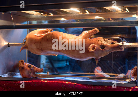 Das Schwein am Spieß dreht. sele geröstet in das Glas ist Ofen auf dem Markt. Straße Verkauf von Schweinefleisch. gegrillte Schwein. Stockfoto