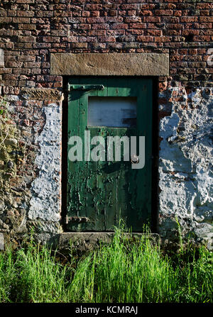 Alten grünen Holztür mit abblätternder Farbe in einer alten Scheune in Lancashire, Großbritannien Stockfoto