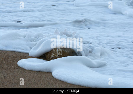 Einzigen Stein in der Brandung am Strand, West Bay, Dorset, Großbritannien Stockfoto