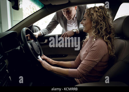 Verkäufer zur Unterstützung von Kunden sitzen im Auto an Showroom Stockfoto