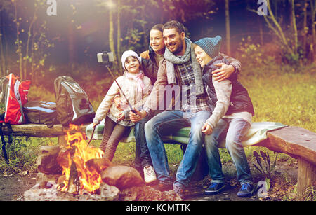 Familie mit Smartphone unter Selfie nahe am Lagerfeuer Stockfoto