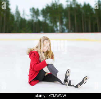 Junge Frau mit Knieverletzung auf der Eislaufbahn Stockfoto