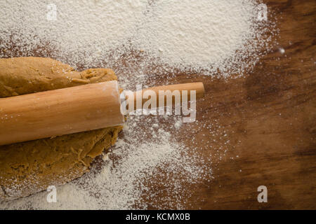 Über dem Kopf der Abflachung Teig mit einem Nudelholz mit über Mehl auf einem Holztisch sprengte Stockfoto