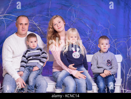 Studio Schoß der großen Familie sitzt auf Weiß Sitzbank im Winter Dekorationen Stockfoto