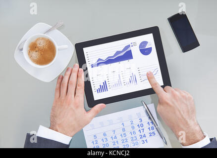 Unternehmer-Hand mit Digital-Tablette zeigt Graph-Diagramm mit Kalender Stockfoto