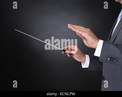 Nahaufnahme der Orchester Dirigent Hände halten Baton auf schwarzem Hintergrund Stockfoto