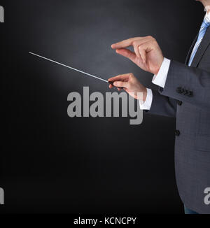 Nahaufnahme der Orchester Dirigent Hände halten Baton auf schwarzem Hintergrund Stockfoto