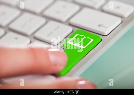 Nahaufnahme der Hand über die grüne Taste mit Buchsymbol Stockfoto