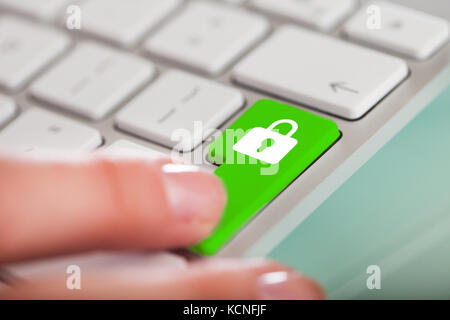 Nahaufnahme der Hand über die grüne Taste mit Lock-Zeichen auf der Tastatur Stockfoto