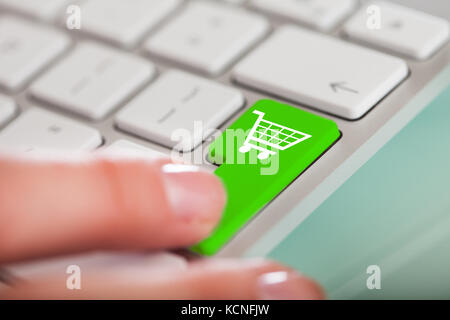 Nahaufnahme der Hand über Shopping Cart Symbol Taste auf der Tastatur Stockfoto
