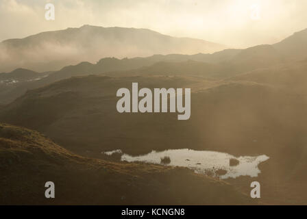 Morgendämmerung über Loughrigg, mit tief liegenden Wolken, kleiner tarn im Vordergrund, in der Nähe von Ambleside, Lake District National Park, Großbritannien Stockfoto