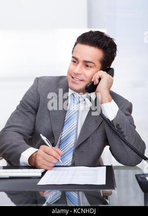 Porträt der jungen Unternehmer am Schreibtisch mit Telefon Stockfoto