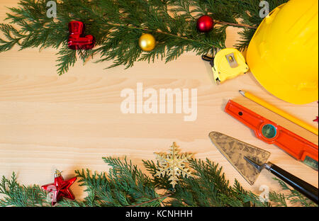 Schutzhelm, Maurer Werkzeuge und Weihnachtsschmuck auf hölzernen Hintergrund Stockfoto