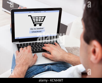 Geschäftsmann mit Laptop mit Online-Shopping-Anwendung auf einem Bildschirm Stockfoto