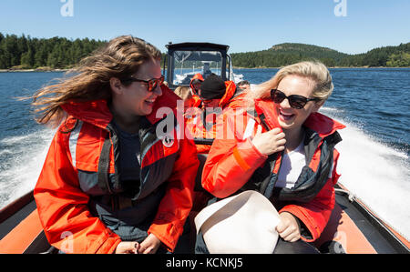 Zwei Freunde erleben eine Walbeobachtungstour von der Vorderseite ihres Zodiaks südlich von Seymour Narrows. Campbell River, Vancouver Island, British Columbia, Kanada. Stockfoto