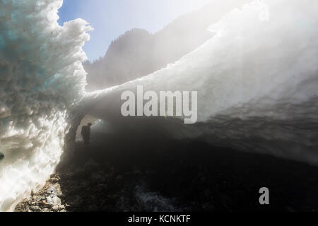 Ein Wanderer geht durch eine schneehöhle am Sockel des Jahrhunderts sam See, Strathcona Park, Vancouver Island, British Columbia, Kanada. Stockfoto