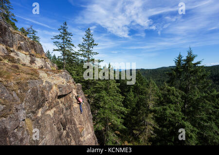 Eine Kletterin bestiegen eine Route auf einem der Klettergebiete nahe dem Chinesischen Berg. Quadra Island. Stockfoto