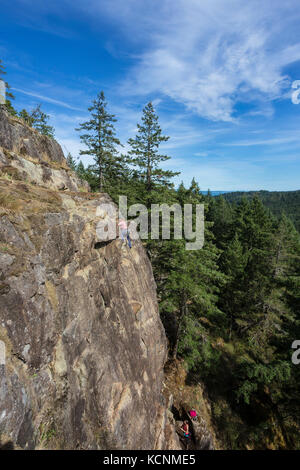 Eine Kletterin bestiegen eine Route auf einem der Klettergebiete nahe dem Chinesischen Berg. Quadra Island. Stockfoto