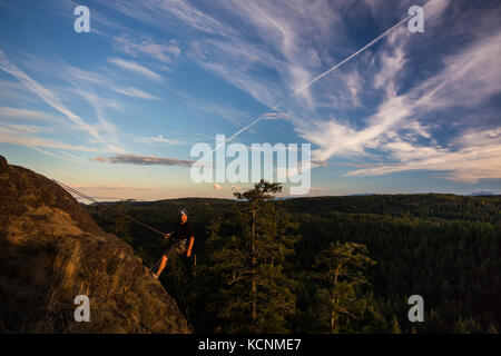 Ein Bergsteiger rappels nach Sonnenuntergang Platte nach einem Aufstieg auf eine der unteren Schichten der chinesischen Berg, Quadra Island, Discovery Inseln Stockfoto