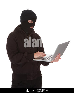 Einbrecher mit Maske mit Laptop auf weißem Hintergrund Stockfoto