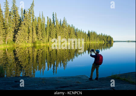 Wanderer mit Tablet entlang der Grass River oben Pisew Falls, Pisew Falls Provincial Park, Manitoba, Kanada Stockfoto