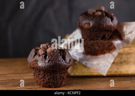 Zwei frisch ausgepackten Schokolade chunks Muffins auf dunklem Holz Tisch Stockfoto