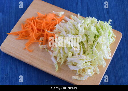 Gehackten Kohl und Möhren auf einem hölzernen Schneidebrett. Schritt für Schritt kochen Stockfoto