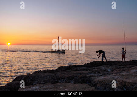 Fischer bei Sonnenuntergang. Bagni della Regina Giovanna (Punta del Capo) Stockfoto