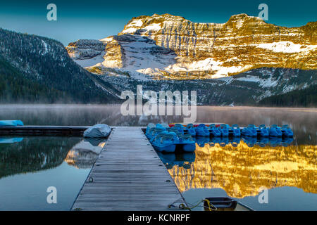 Cameron Lake im Morgenlicht mit hölzernen Pier und Kanu, mit Berg Reflexionen in See. Waterton National Park, Alberta, Kanada Stockfoto