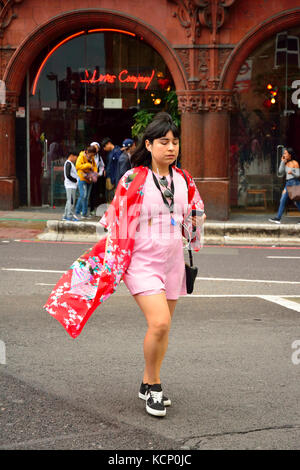 Frau überfahrt-Straße, während Sie gleichzeitig ein Smartphone und das Tragen von Kopfhörern in London, England, Großbritannien Stockfoto