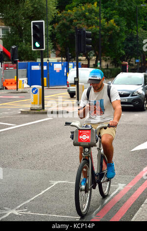 Radfahrer mit Smartphone während Reiten in London, Großbritannien Stockfoto