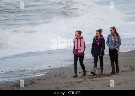 Aberystwyth Wales UK, Samstag 07 Oktober 2017 UK Wetter: drei junge Frauen, die an einem bewölkten und luftigen Herbstnachmittag am Strand entlang laufen, in Aberystwyth Wales Foto: keith morris/Alamy Live News Stockfoto