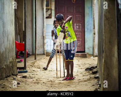 Koralawella, Westprovinz, Sri Lanka. Oktober 2017. Kinder spielen in einer Gasse zwischen den Häusern in einem Fischerdorf etwa 40 Minuten südlich von Colombo ein Cricket-Spiel. Die Fischerei ist für viele der Menschen an der Küste Sri Lankas eine wichtige Wirtschaftstätigkeit. Sri-Lankaner sind besessen von Cricket, einem Spiel, das seinen Ursprung im kolonialen Indien hat. Quelle: Jack Kurtz/ZUMA Wire/Alamy Live News Stockfoto