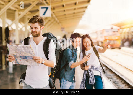 Multiethnische Gruppe von Rucksack Reisenden mit Karte und Smartphone Navigation am Bahnhof, asiatischen Tourismus Aktivität oder mobile phone technology Konzept Stockfoto