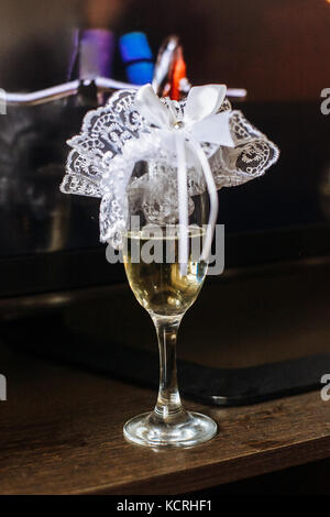 Strumpfband der Braut, die auf ein Glas Champagner, unscharfer Hintergrund. Stockfoto