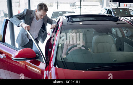 Verkäufer stehen Kunden sitzen im Auto an Showroom Stockfoto