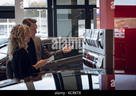 Weibliche Kunden Farbmuster, während durch Verkäufer im Autohaus stand Stockfoto