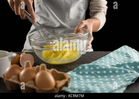 Den mittleren Abschnitt der Frau schlagen, Eier mit einem Schneebesen in einer Schüssel Stockfoto