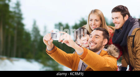 Glückliche Freunde mit Kamera auf Eisbahn Stockfoto