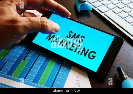 Mann, Smartphone mit Worten sms-Marketing. Stockfoto