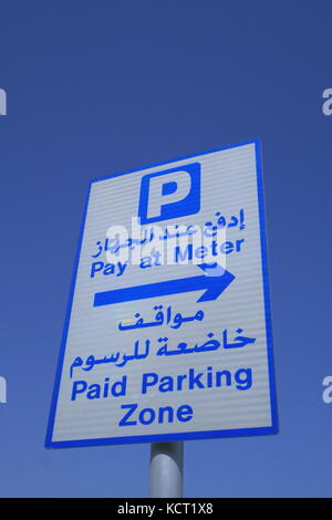 Ein straßenschild in Arabisch und Englisch Information der Fahrer, dass Sie sich in einer gebührenpflichtigen Parkzone und sollten bei großen Zahlen. Stockfoto