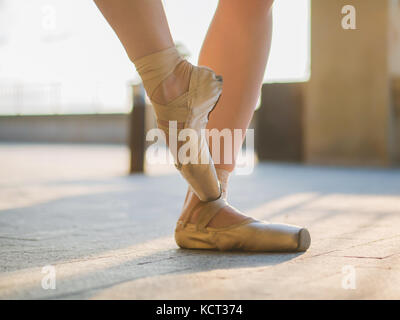 Nahaufnahme der Füße ist ein Tänzer, wie sie Praktiken Übungen auf dem Stein Damm pointe. Woman's Füße in Pointe Shoes. Ballerina zeigt klassische Ba Stockfoto