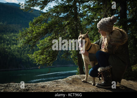 Frau mit Hund Entspannung in der Nähe des Flusses an einem sonnigen Tag Stockfoto